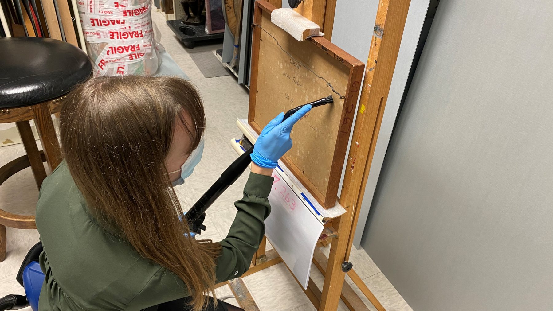 Conservator vacuuming mold from the back of a canvas painting